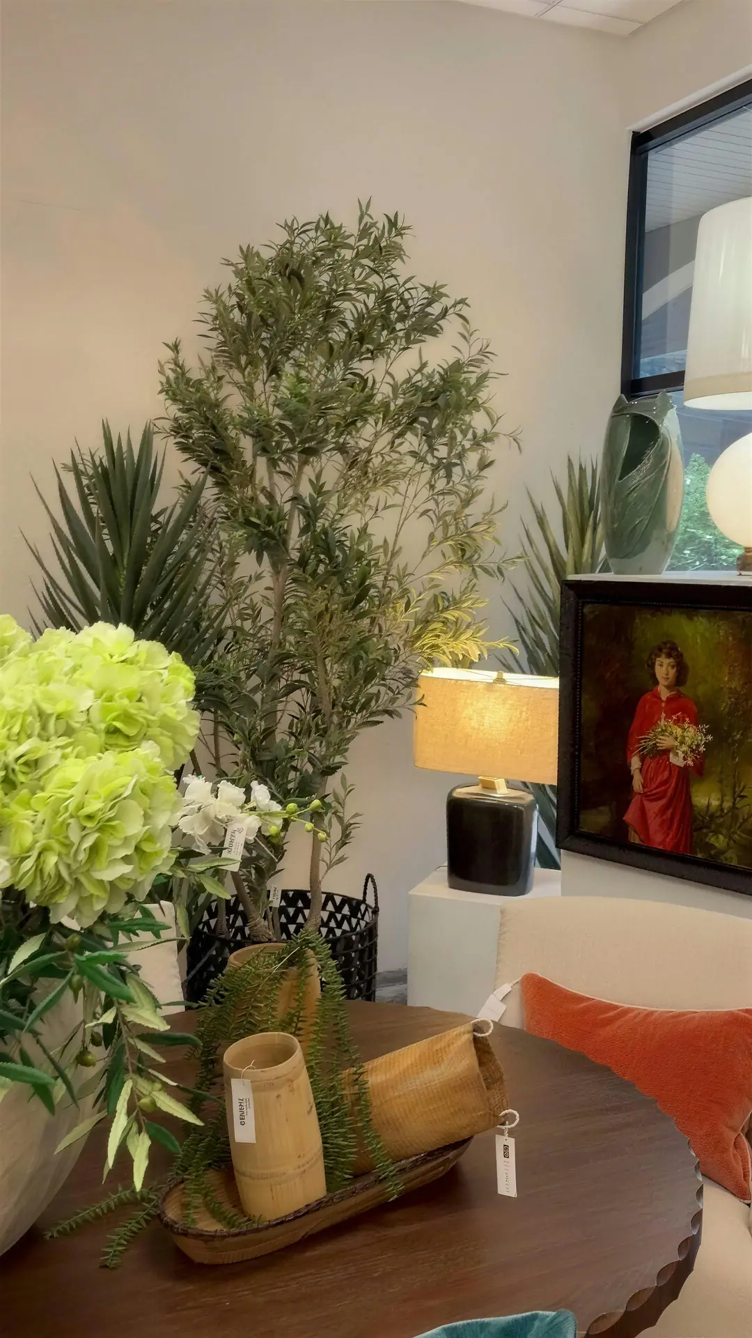 Olive tree, florals and a framed portrait styled on a wood table