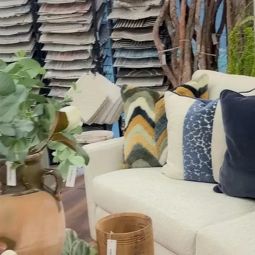 A stack of patterned rugs beside a sofa