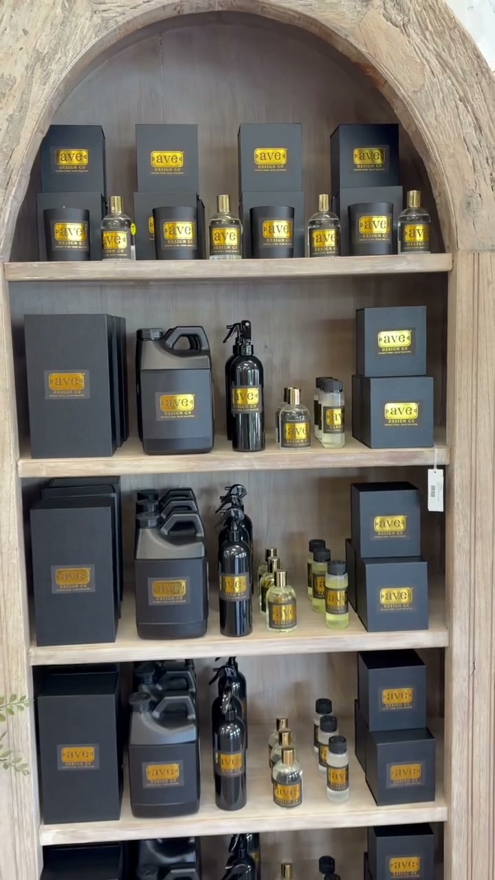 The AVE Design Co line on its arched shelf in the store: black boxes with gold labels, refill jugs and spray bottles