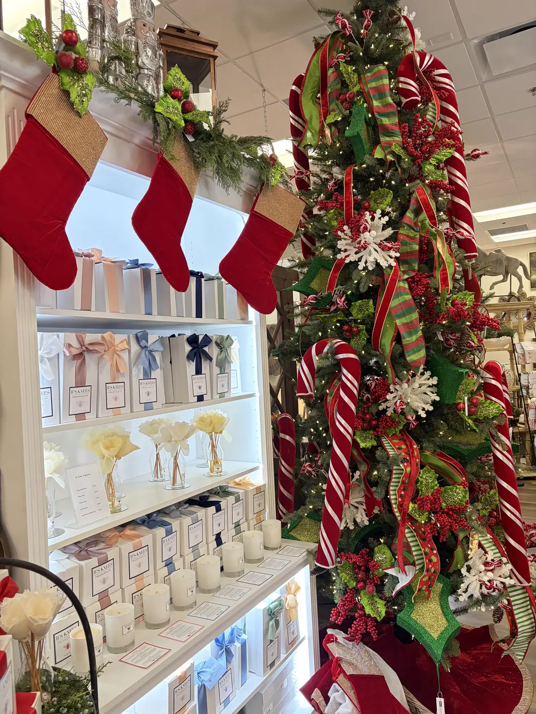 A Christmas tree wrapped in candy canes and ribbon, with red stockings over the candle shelves in the store